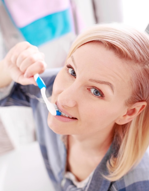 Zdjęcie kobieta szczotkuje zęby trzymając szczoteczkę do zębów opieka stomatologiczna z bliska portret pięknej dziewczyny szczotkuje zęby uśmiechając się szczęśliwy patrząc na kamerę