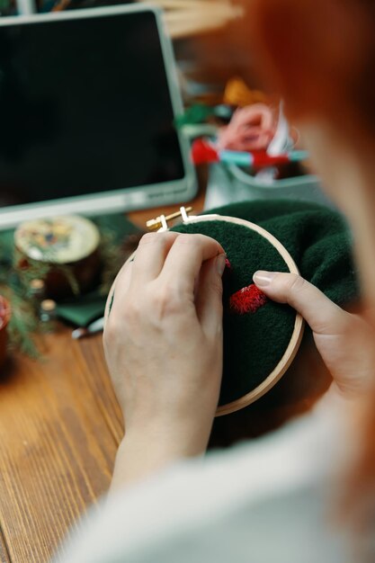 Zdjęcie kobieta szyjąca na zielonej tkaninie dziewczęta ręce haftowanie grzyby kapelusz na ramie koncepcja hobby