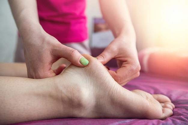 Kobieta terapeutka robi masowaniu nóg klientki