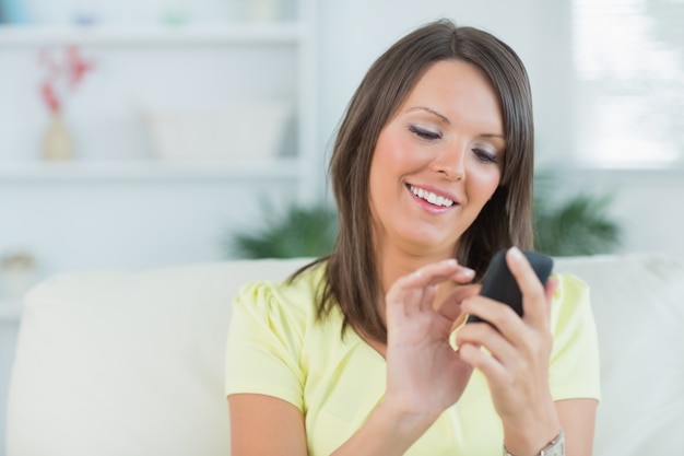 Kobieta texting z jej smartphone w żywym pokoju