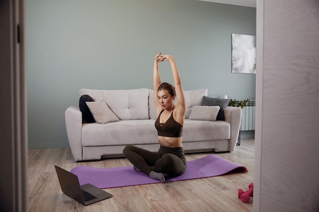 Zdjęcie kobieta trenująca w domu i oglądająca filmy na laptopie, dziewczyna ćwicząca