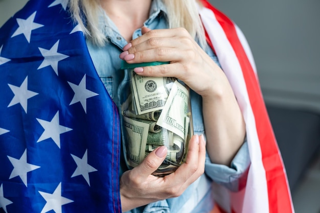 Zdjęcie kobieta trzyma dolarów w szklanym słoju i amerykańską flagę.