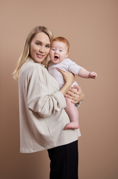 Kobieta trzyma dziecko w ramionach. Portret młodej matki po urodzeniu dziecka. Młoda rodzina