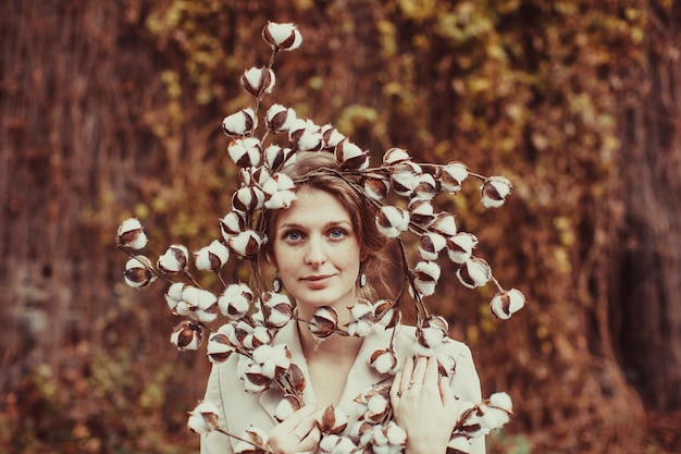 Kobieta trzyma gałąź bawełny kwiaty na tle przyrody.