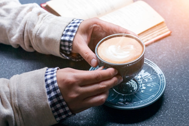 Kobieta trzyma gorącej filiżanki kawy latte blisko nadokiennego ranku światło ręki.