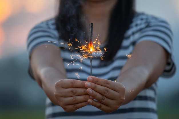 Kobieta trzyma i bawić się z pożarniczymi sparklers na festiwalu w ryżowym polu przy zmierzchu czasem