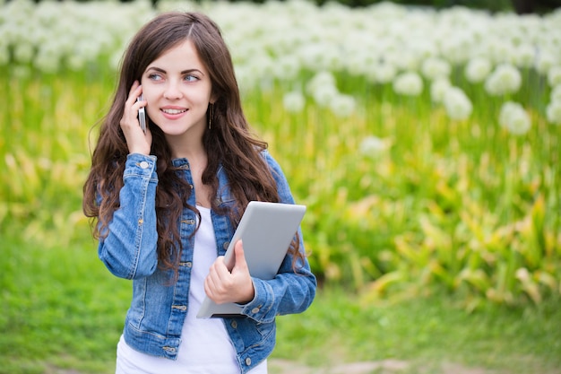 Kobieta trzyma komputer typu tablet i rozmawia przez telefon