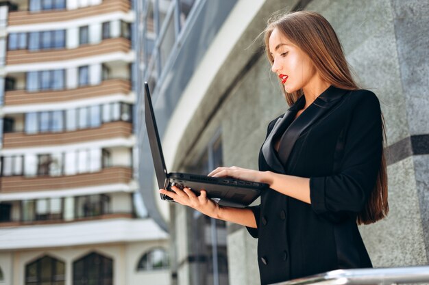 Kobieta trzyma laptop wewnątrz on wręcza i pisać na maszynie