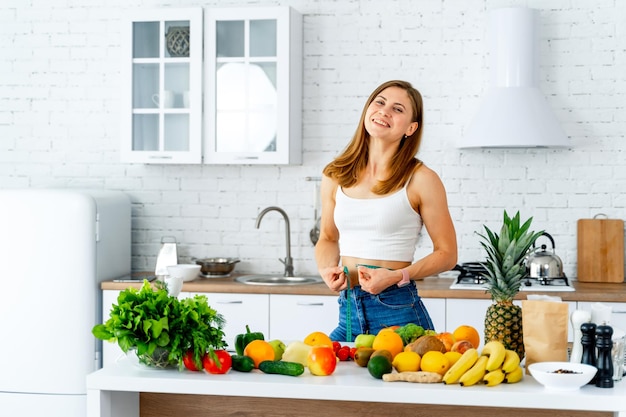 Kobieta trzyma miarkę wokół talii Dużo owoców i warzyw na stole Dieta