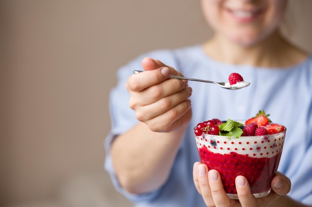 Kobieta trzyma miskę smoothie z organicznymi jagodami jogurtowymi i miętą Domowy jogurt w rękach dziewczynki