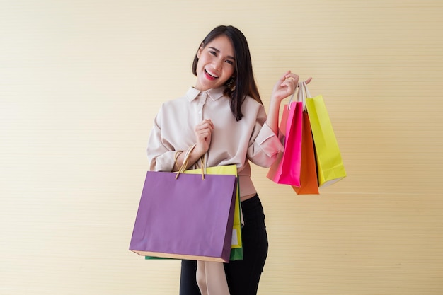 Kobieta trzyma papierowe torby z uśmiechem na żółtym tle w koncepcji zakupy.