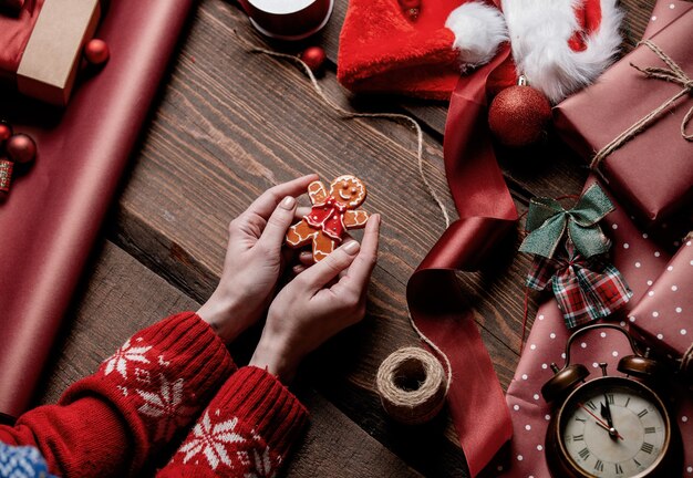 Kobieta trzyma plik cookie piernika na drewnianym stole w czasie pakowania