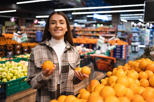 Kobieta trzyma pomarańcze w dziale owoców supermarketu