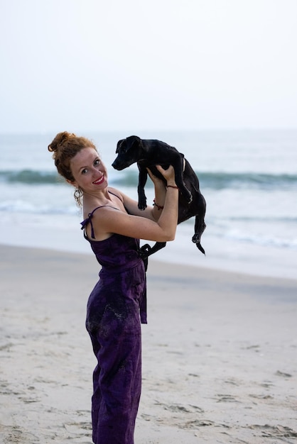 Kobieta trzyma psa na plaży.