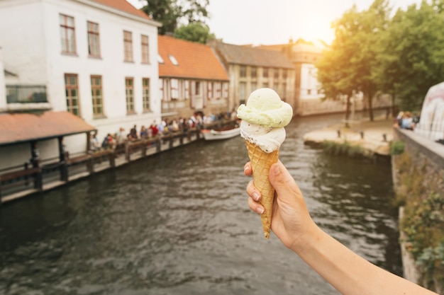 Kobieta trzyma pyszne lody na tle kanału w Brugii w Belgii