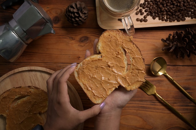Kobieta trzyma pyszne tosty z masłem orzechowym na drewnianym stole.
