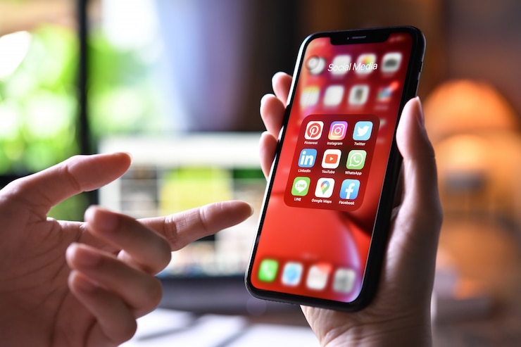 Zdjęcie kobieta trzyma smartphone z ikonami ogólnospołeczni środki na ekranie w domu
