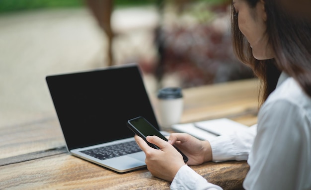 Kobieta trzyma tekst lub wiadomość na telefonie komórkowym Kobieta używa smartfona do przeglądania sieci, pracy laptopa, handlu akcjami