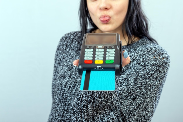 Kobieta trzyma terminal płatniczy i pokazuje język