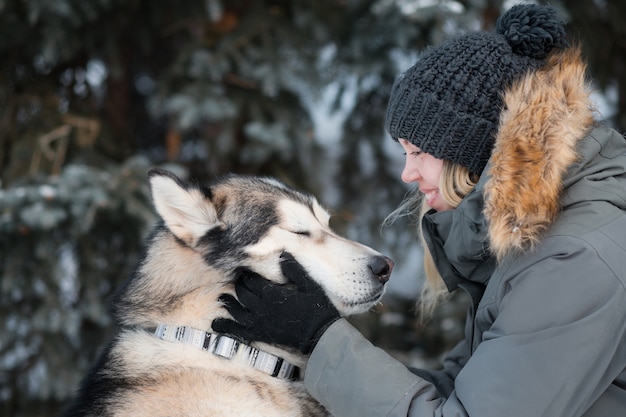 Kobieta Trzyma Twarz Alaskan Malamute Z Zamkniętymi Oczami Z Przyjemności W Zimie