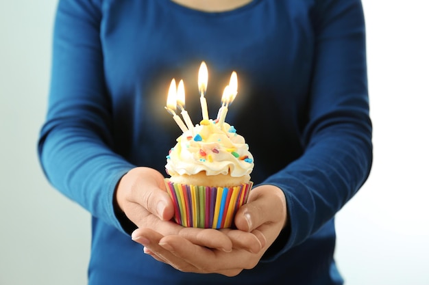 Kobieta trzyma urodzinową babeczkę ze świeczkami w ręki zbliżeniu