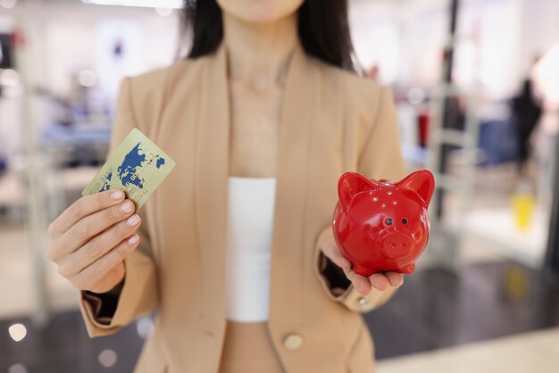 Kobieta Trzyma W Ręku Plastikową Kartę Kredytową I Czerwoną świnię Skarbonkę