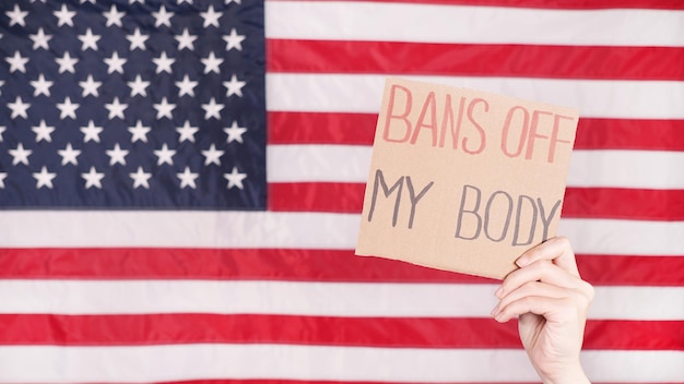 Kobieta trzyma znak Bans Off My Body Amerykańska flaga na tle