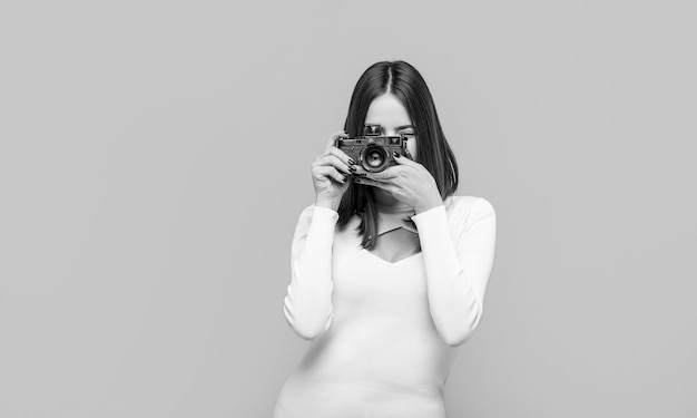 Kobieta trzymająca aparat na żółtym tle Dziewczyna używająca aparatu fotograficznego Fotograf aparat fotograficzny fotografujący dziewczynę radość sprawia, że robienie zdjęć robi koncepcję Dziewczyna z aparatem
