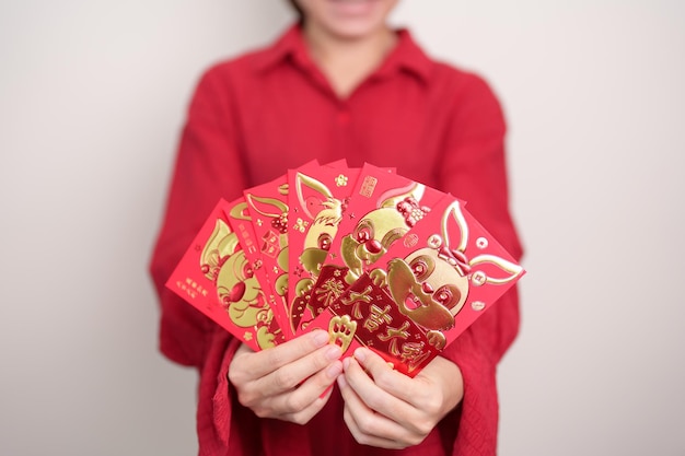 Kobieta trzymająca chińską czerwoną kopertę ze złotym królikiem i błogosławieństwem prezent pieniężny na szczęśliwe święto Nowego Roku Księżycowego Chińskie zdanie oznacza szczęście zdrowe Szczęśliwy i bogaty