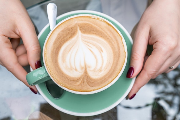 Kobieta Trzymająca Filiżankę Kawy Cappuccino Z Pianką W Kształcie Serca W Kawiarni Lub Kawiarni Na Chodniku Widok Z Góry