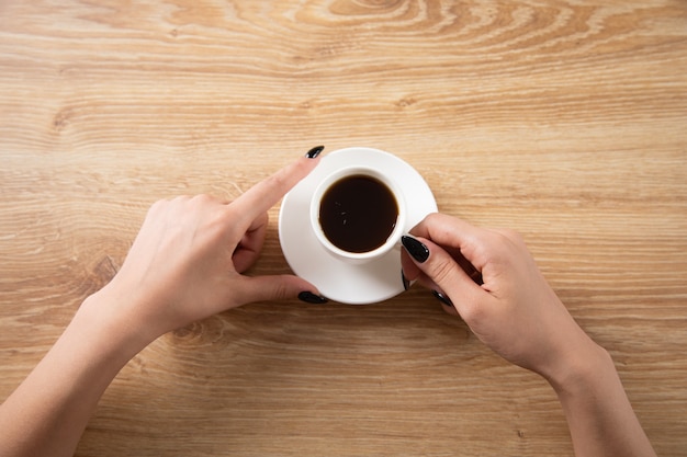 Kobieta trzymająca filiżankę kawy na stole