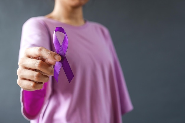 Kobieta trzymająca fioletową wstążkę na szarym tle zbliżenie Symbol świadomości przemocy domowej