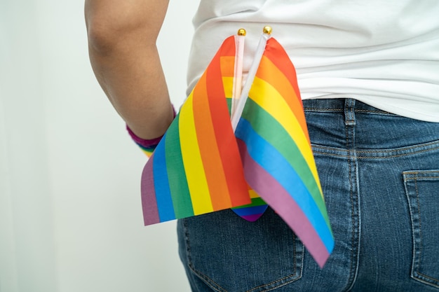 Kobieta trzymająca kolorową tęczową flagę LGBT, symbol praw człowieka lesbijek, gejów, biseksualistów i transseksualistów