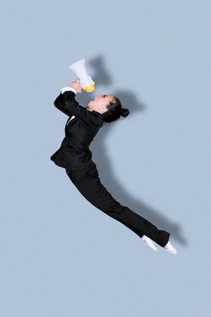 Zdjęcie kobieta trzymająca megafon podczas tańca na szarym tle