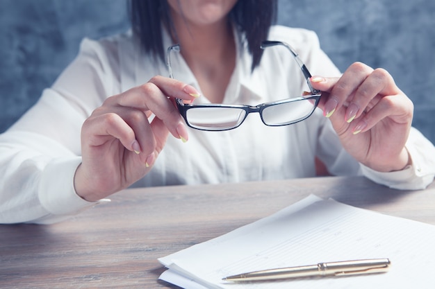Kobieta trzymająca okulary optyczne siedząc przy stole