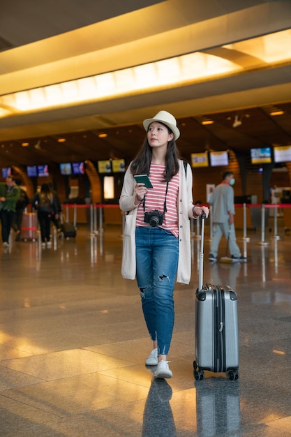 kobieta trzymająca paszport na lotnisku. w tle stanowiska odprawy.