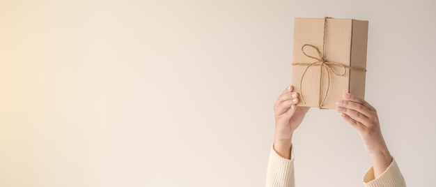Kobieta trzymająca się za ręce trzymające pudełko z kokardą Minimalistyczna koncepcja dawania prezentu