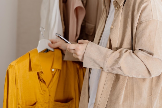 Kobieta trzymająca smartfona i robiąca zdjęcie swoich starych ubrań, aby je sprzedać online Sprzedaż na stronie internetowej e-commerce Ponowne wykorzystanie koncepcji używanych Świadomy konsument, zrównoważony styl życia Widok z bliska