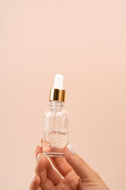 Zdjęcie kobieta trzymająca szklaną butelkę z zakraplaczem produktu do prezentacji żelowego serum-oleju