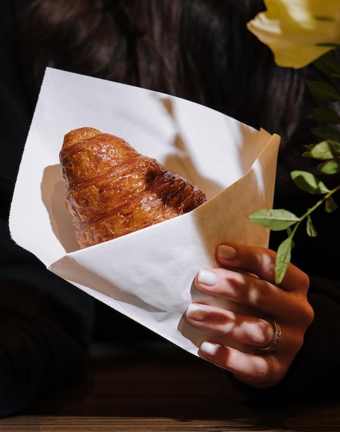 Kobieta trzymająca w ręku croissant w kawiarni