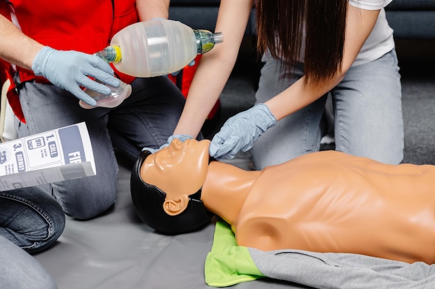 Kobieta trzymająca worek do oddychania Worek Ambu Demonstracja resuscytacji krążeniowo-oddechowej Szkolenie z resuscytacji krążeniowo-oddechowej procedura medyczna na lalce CPR w klasie Ratownik medyczny demonstruje praktykę pierwszej pomocy w celu ratowania życia