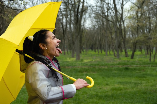 Kobieta trzymająca żółtą parasolkę przeciwko drzewom