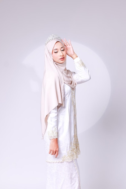 Kobieta ubrana w biały hidżab i białą sukienkę z motywem kwiatowym.