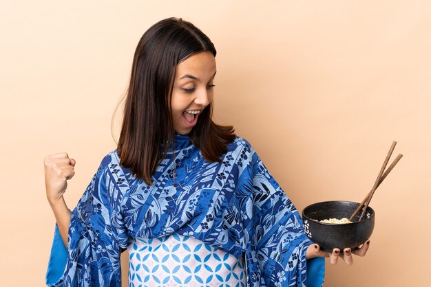 Kobieta ubrana w kimono i trzymając miskę zupy z makaronem