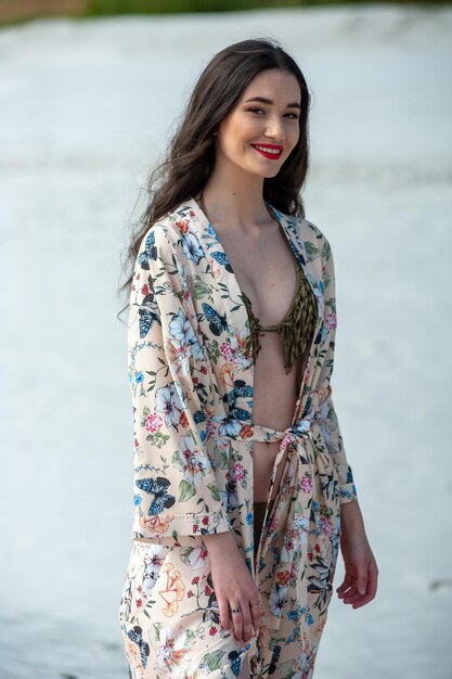 Kobieta ubrana w kwieciste kimono stoi na plaży.