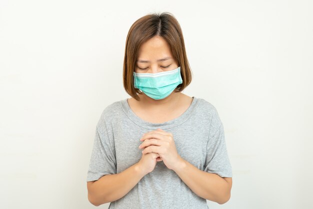 Kobieta ubrana w maskę do ochrony koronawirusa i ręce modlące się do boga