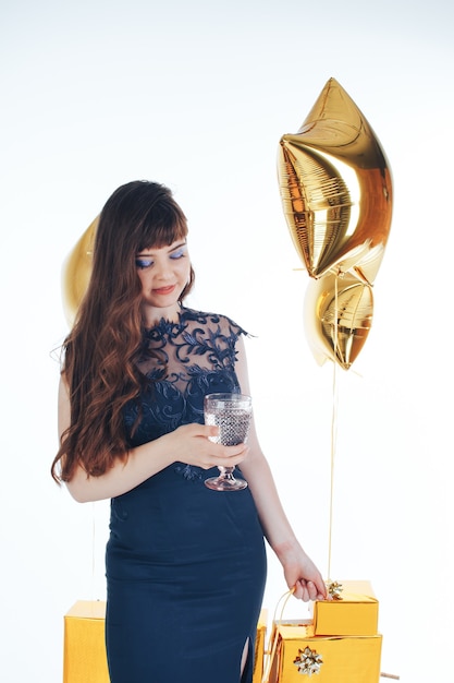 Kobieta ubrana w wieczorową sukienkę z lampką szampana ze złotą nadmuchiwaną gwiazdą