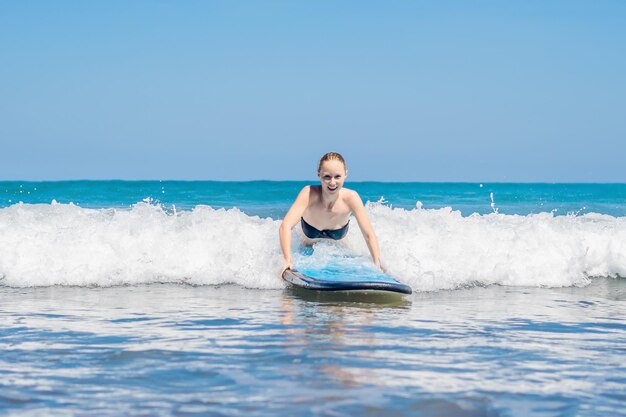 Kobieta uczy się surfować po piance. Bali, Indonezja