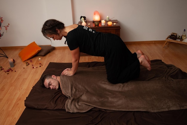 Kobieta uprawiająca jogę na łóżku z mężczyzną na plecach.