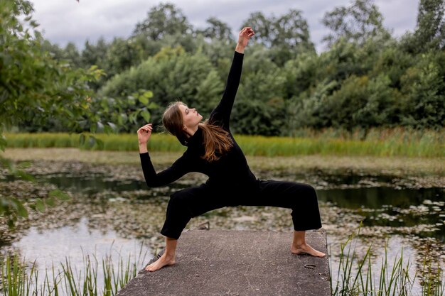 Kobieta uprawiająca jogę na przystani z jeziorem w tle